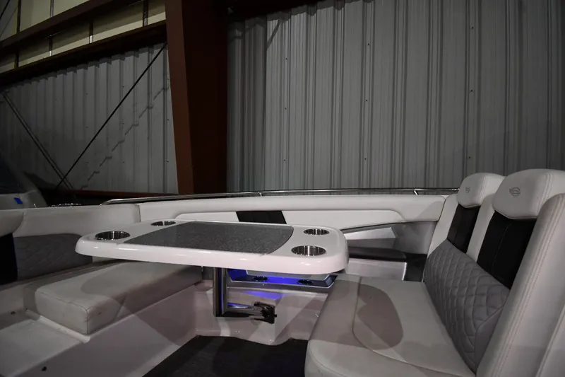 Slide: The Image of 2014 Chaparral 327 SSX boat interior with seating and table in a storage facility. - 18