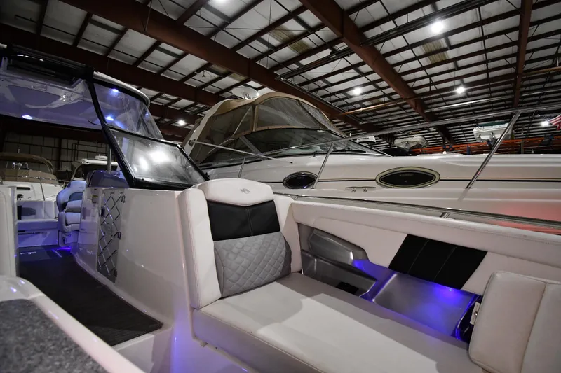 Slide: The Image of 2014 Chaparral 327 SSX boat interior with modern seating and ambient lighting in a showroom. - 21