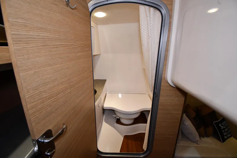 Slide: The Image of 2014 Chaparral 327 SSX boat interior bathroom with wooden door and compact design. - 27