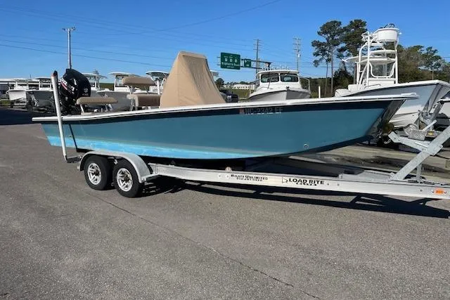 Slide: The Image of 2017 Intruder 23 boat on trailer, parked in marina lot under clear sky. - 2