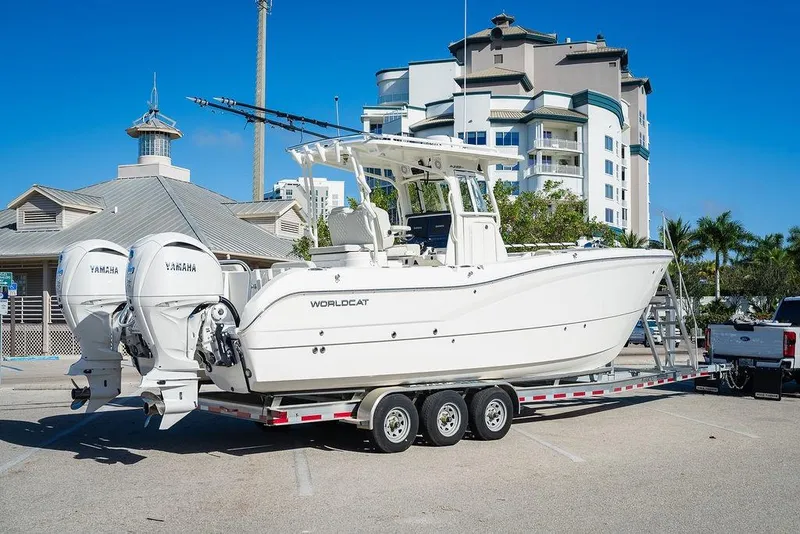 Slide: The Image of 2024 World Cat 295 CC boat on trailer, parked near modern buildings. - 23