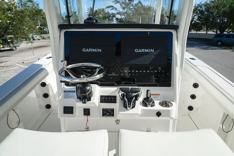 Slide: The Image of 2024 World Cat 295 CC boat dashboard with Garmin navigation displays and steering wheel. - 32