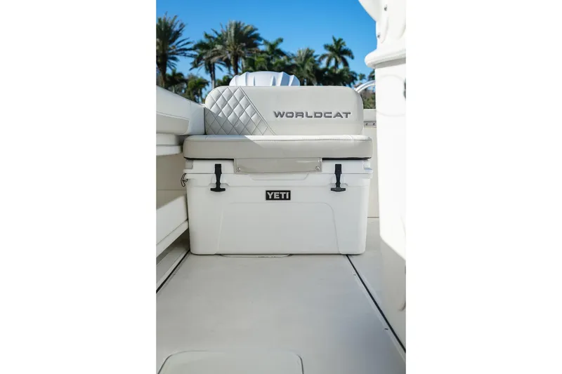 Slide: The Image of 2024 World Cat 295 CC boat seat with Yeti cooler, palm trees in background. - 34