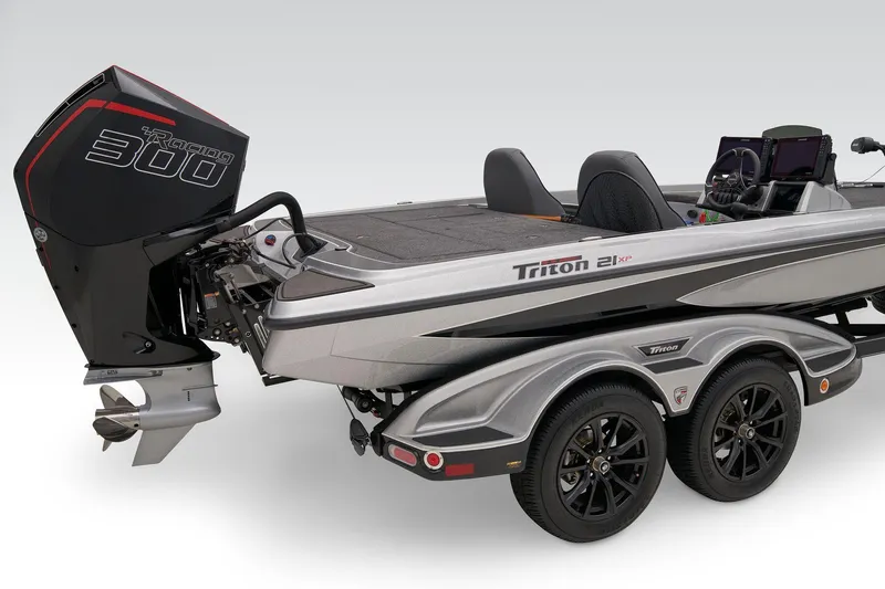 Slide: The Image of 2026 Triton 21XP Patriot boat deck with Lowrance equipment, parked near grass and tractor. - 12