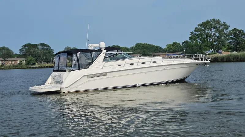 The Image of 1999 Sea Ray 500 Sundancer yacht cruising on a calm river with trees in the background. - 0