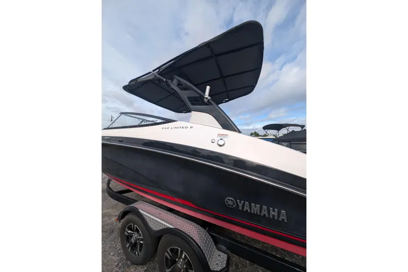 Slide: The Image of 2014 Yamaha Boats 242 Limited S with canopy, on trailer, under blue sky. - 2