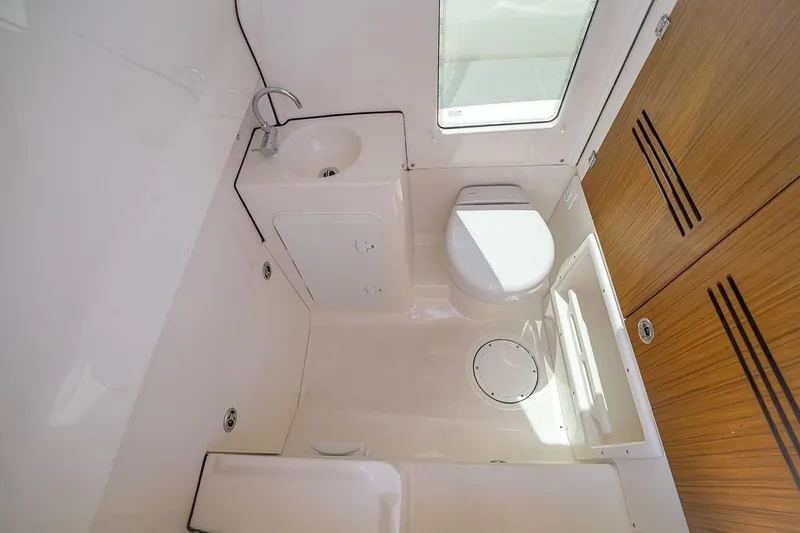 Slide: The Image of Manufacturer Provided Image: 2026 Solace 28 HCS boat bathroom with sink, toilet, and wooden storage cabinets. - 6