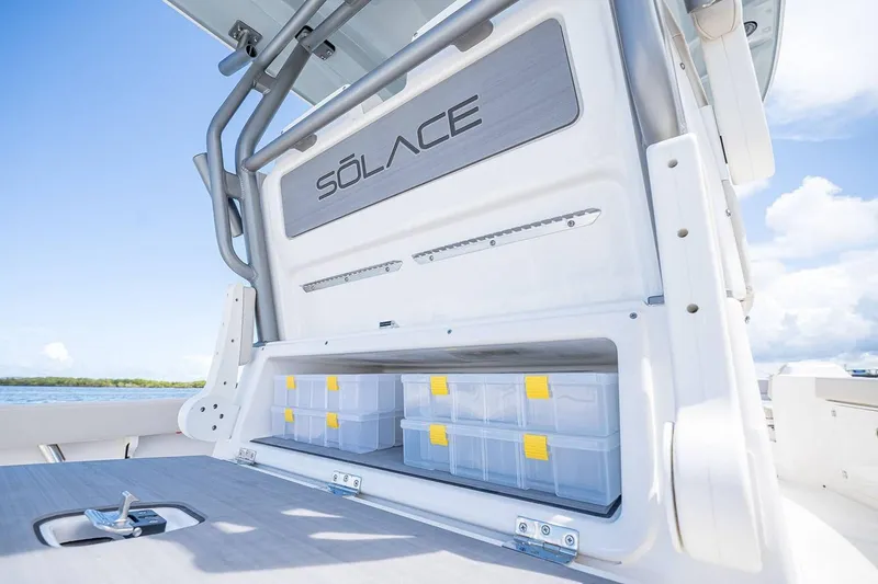 Slide: The Image of Manufacturer Provided Image: 2026 Solace 28 HCS boat storage compartment with clear boxes, open on a sunny day. - 8