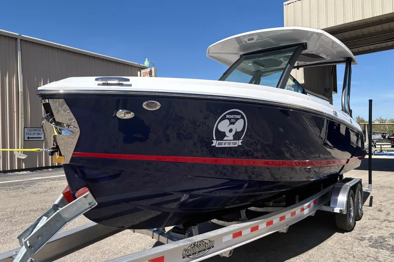 Slide: The Image of 2026 Monterey Elite 25 SD boat on trailer, blue hull with red stripe, parked outdoors. - 3