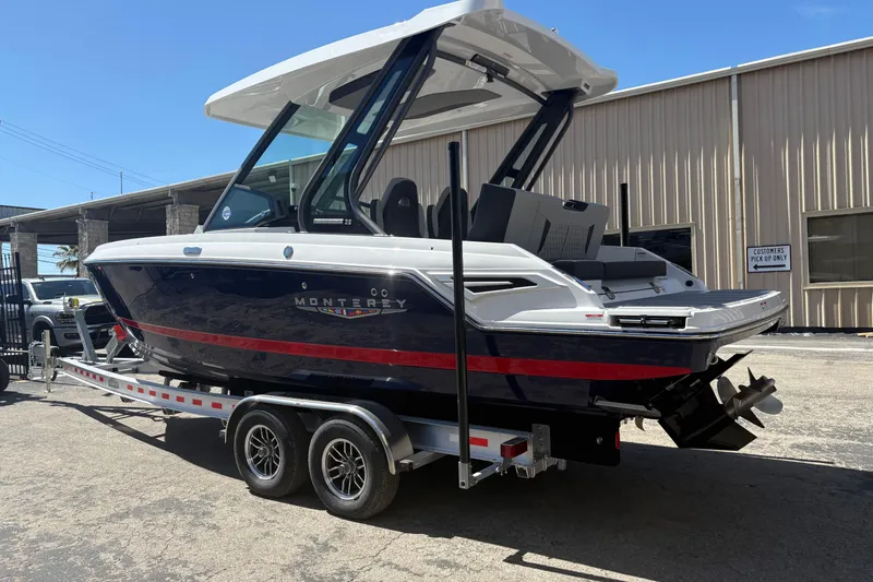 Slide: The Image of 2026 Monterey Elite 25 SD boat on trailer, parked outside a warehouse. - 5