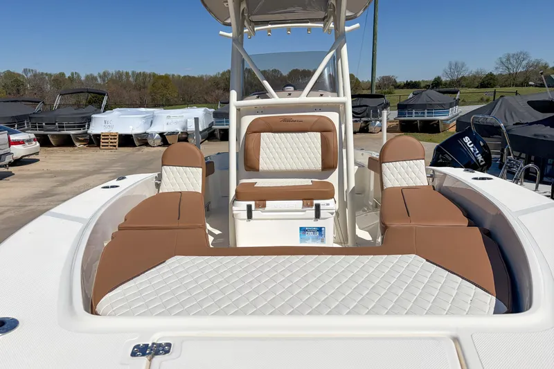 Slide: The Image of 2026 Pioneer 220 Bay Sport boat with tan and white seating, parked outdoors. - 10