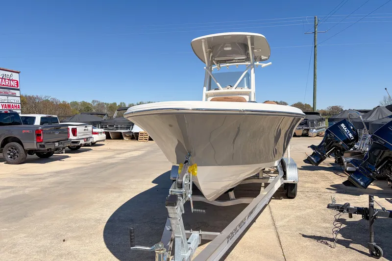 Slide: The Image of 2026 Pioneer 220 Bay Sport boat on trailer at dealership, surrounded by trucks and outboard motors. - 13