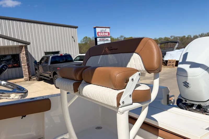 Slide: The Image of 2026 Pioneer 220 Bay Sport boat seat with brown and white upholstery at a marina. - 8
