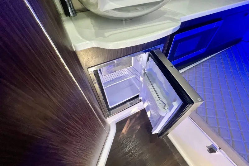 Slide: The Image of 2020 Edgewater 370CC interior with open mini fridge, modern design, and blue ambient lighting. - 15