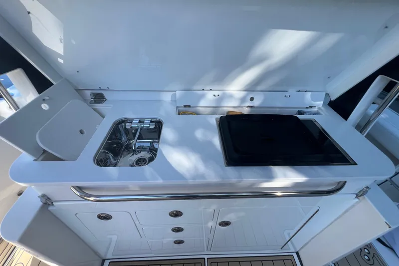 Slide: The Image of 2020 Edgewater 370CC boat galley with sink and stove, featuring sleek white design. - 24