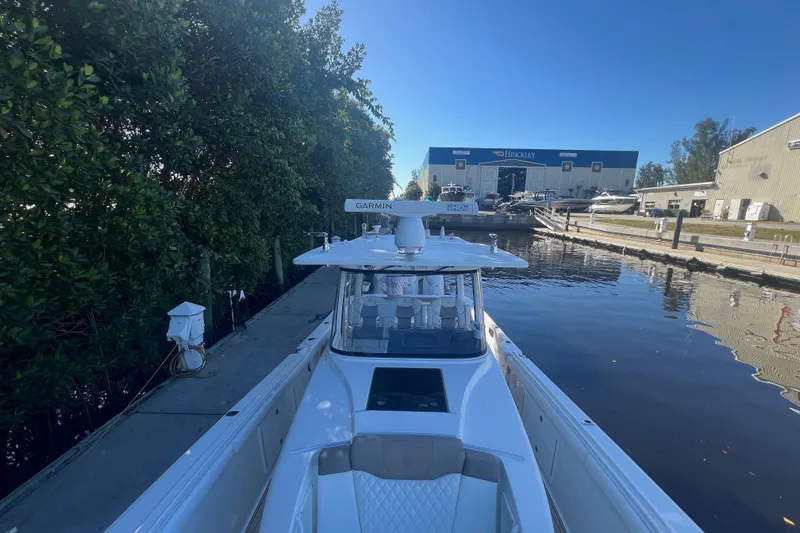 Slide: The Image of 2020 Edgewater 370CC boat docked near marina, surrounded by greenery and industrial buildings. - 32