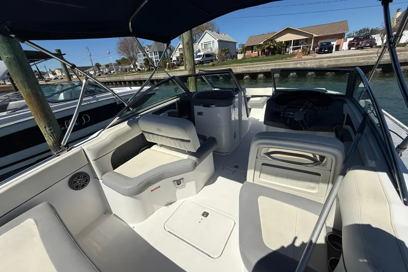 Slide: The Image of 2020 Cobalt CS23 boat interior with seating and steering, docked by waterfront homes. - 10