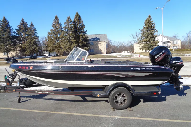 The Image of 2014 Ranger 1850 LS boat on trailer with Mercury outboard motor, parked outdoors. - 0