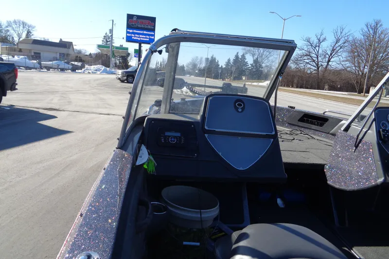 Slide: The Image of 2014 Ranger 1850 LS boat interior with dashboard and windshield, parked outdoors. - 38