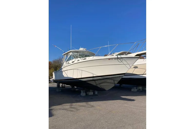 The Image of 1999 Wellcraft 330 Coastal boat on dry dock under clear blue sky. - 1