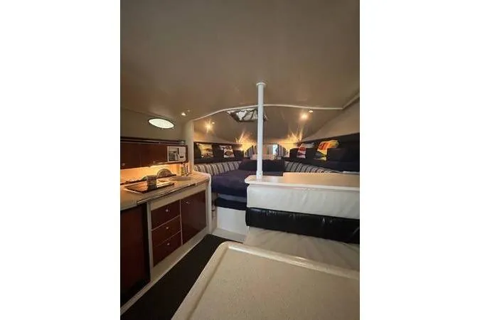 Slide: The Image of 1999 Wellcraft 330 Coastal cabin interior with cozy seating and kitchenette. - 2