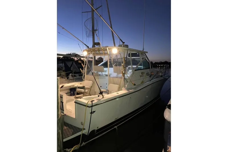 Slide: The Image of 1999 Wellcraft 330 Coastal boat docked at sunset, illuminated deck lights. - 5