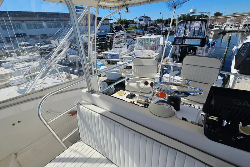 Slide: The Image of 2004 Luhrs 34 Convertible boat interior at marina, featuring helm and seating area. - 24