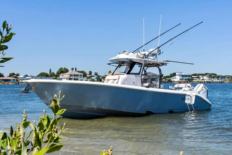 Slide: The Image of Manufacturer Provided Image: 2026 Solace 32 CS boat anchored in calm waters, with fishing rods and coastal homes in the background. - 2