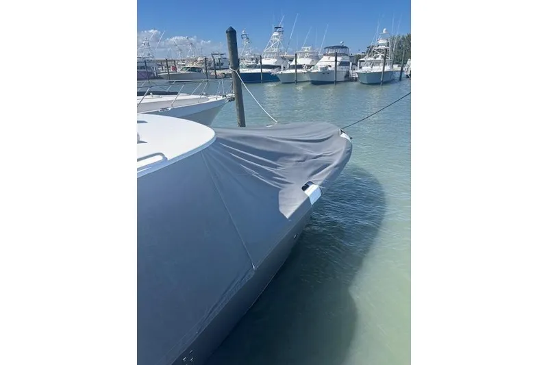 Slide: The Image of 2018 Everglades 435 Center Console boat docked with cover, marina background. - 23