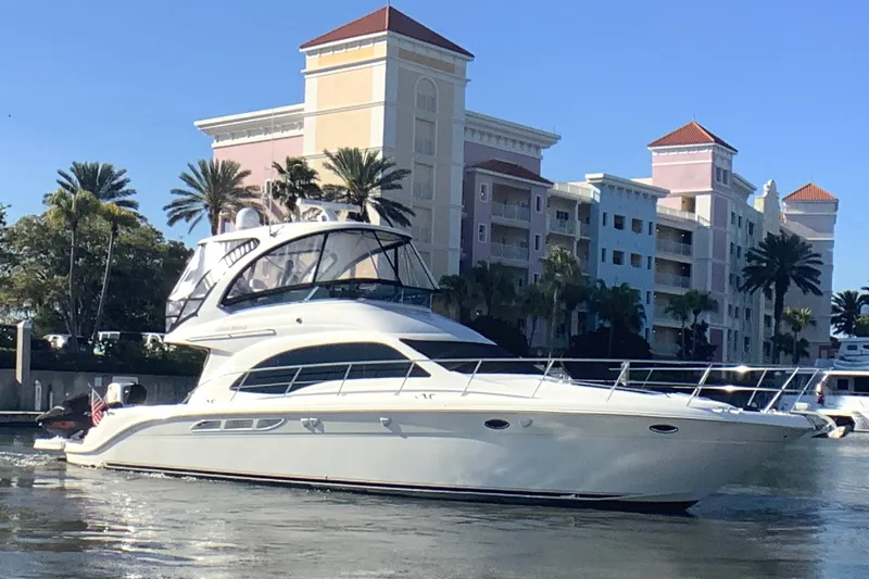 The Image of 2007 Sea Ray 52 Sedan Bridge yacht cruising near waterfront buildings and palm trees. - 0