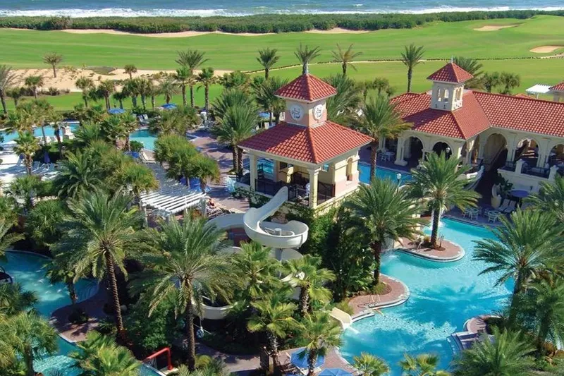 Slide: The Image of Luxurious resort pool area with palm trees and red-roofed buildings near the ocean. - 51