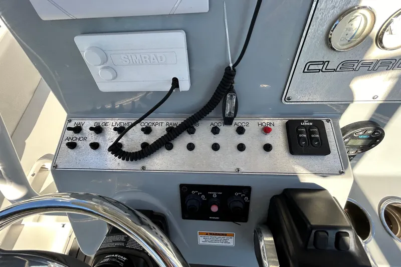 Slide: The Image of Control panel of a 2022 Clearwater 2300 boat with various switches and gauges. - 14