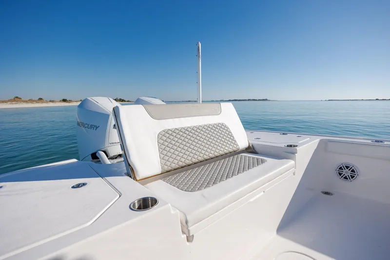 Slide: The Image of 2024 Caymas 281 HB boat with cushioned seating, Mercury engine, and ocean backdrop. - 13