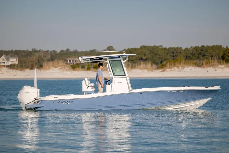 Slide: The Image of 2024 Caymas 281 HB boat cruising on calm water near a sandy shoreline. - 2