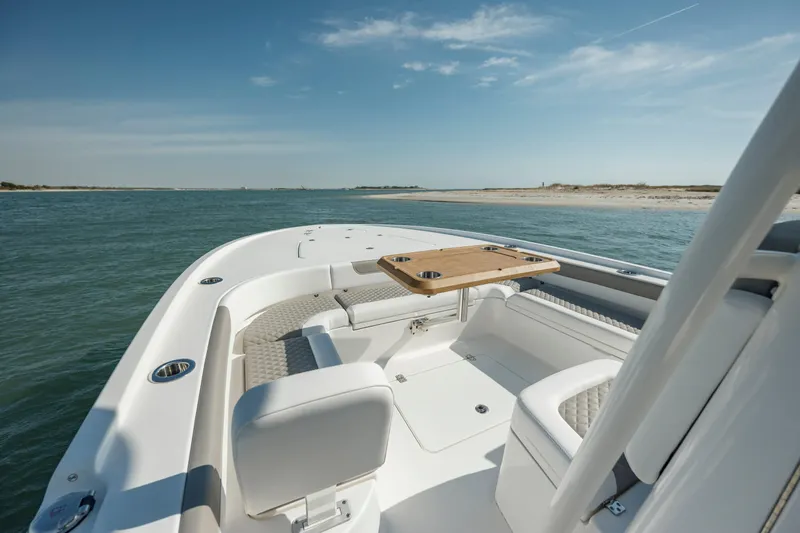 Slide: The Image of 2024 Caymas 281 HB boat interior with seating and table, near a sandy shoreline. - 20