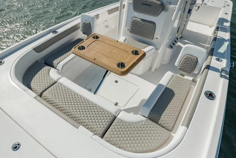 Slide: The Image of 2024 Caymas 281 HB boat interior with cushioned seating and wooden table on water. - 21