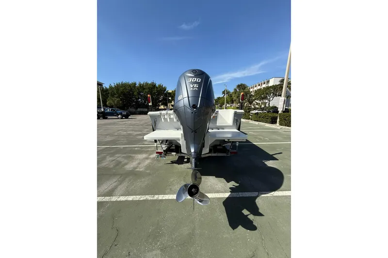 Slide: The Image of 2023 Parker 2320 Sport Cabin boat with powerful outboard motor in a parking lot. - 16