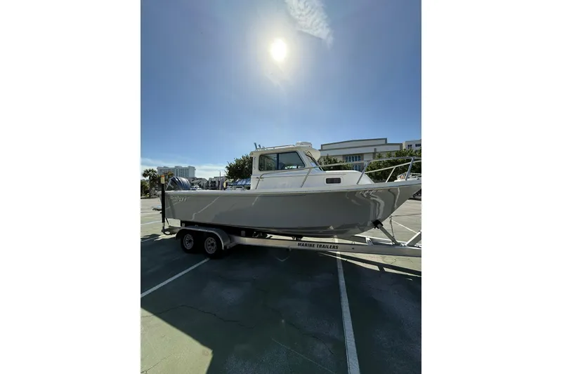 Slide: The Image of 2023 Parker 2320 Sport Cabin boat on trailer under sunny sky. - 21