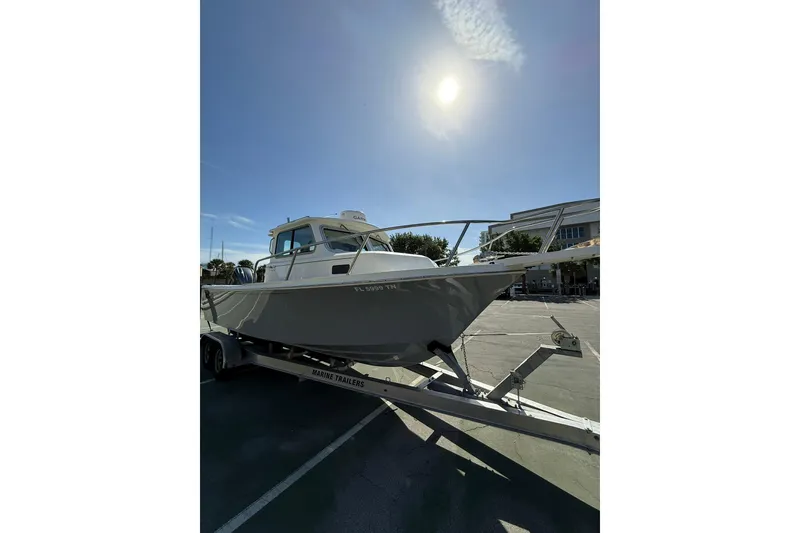 Slide: The Image of 2023 Parker 2320 Sport Cabin boat on trailer under sunny sky. - 22