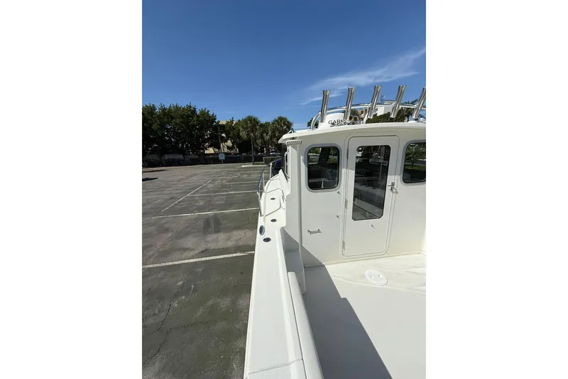 Slide: The Image of 2023 Parker 2320 Sport Cabin boat in a parking lot under clear blue sky. - 36