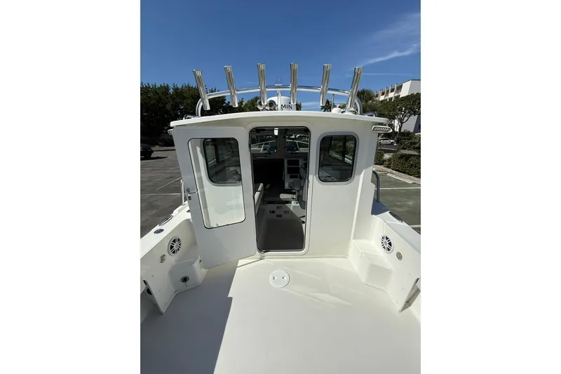 Slide: The Image of 2023 Parker 2320 Sport Cabin boat with open cabin door, docked under clear blue sky. - 49