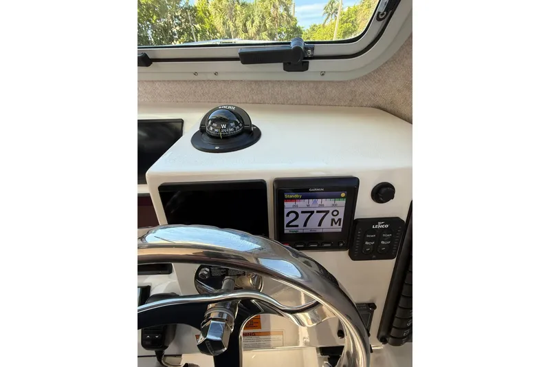 Slide: The Image of 2023 Parker 2320 Sport Cabin dashboard with compass, Garmin display, and steering wheel. - 59