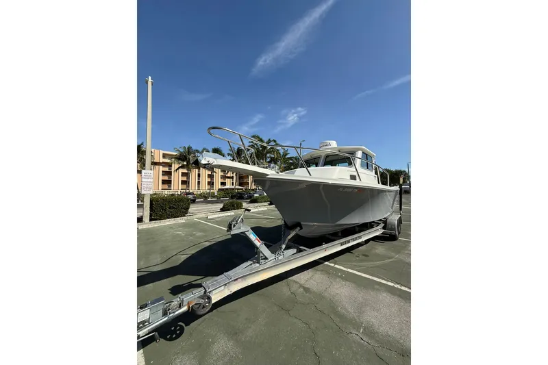 Slide: The Image of 2023 Parker 2320 Sport Cabin boat on trailer in parking lot under clear sky. - 6