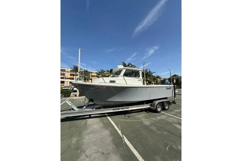Slide: The Image of 2023 Parker 2320 Sport Cabin boat on trailer under clear blue sky. - 8