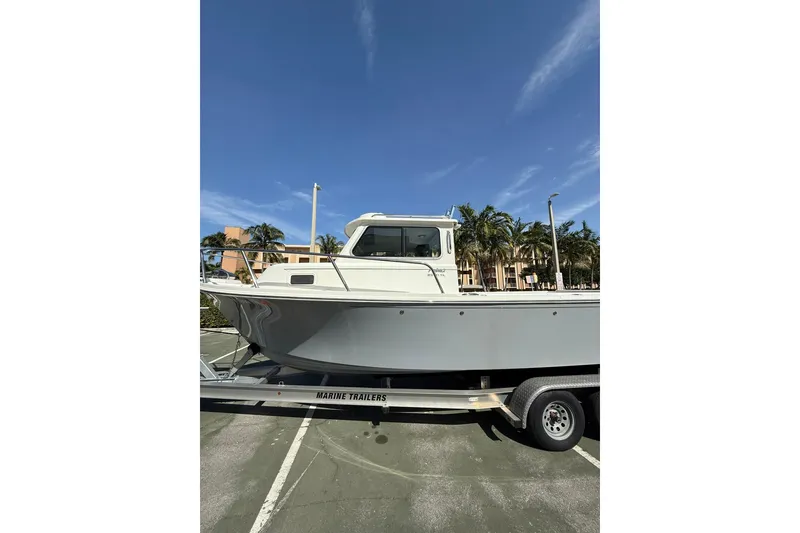 Slide: The Image of 2023 Parker 2320 Sport Cabin boat on trailer under clear blue sky. - 9