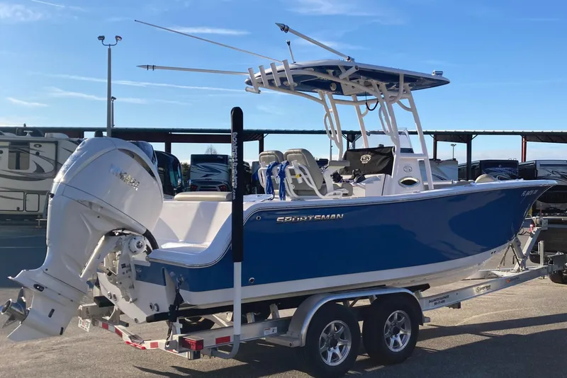 Slide: The Image of 2023 Sportsman Open 242 Center Console boat on trailer, blue hull, parked outdoors. - 2