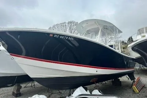 Slide: The Image of 2016 Regulator 25 boat with a sleek navy hull and white top, docked on land. - 2
