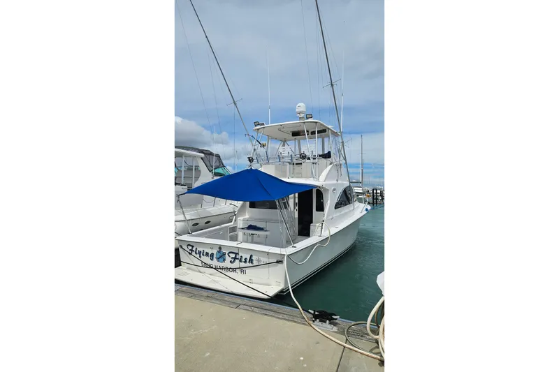 Slide: The Image of Ocean Yachts 40 Super Sport 2000 docked, featuring a blue canopy and fishing equipment. - 84