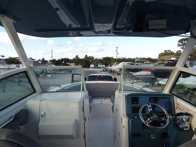 Slide: The Image of 2022 Stingray 269 DC boat interior with steering wheel and seating, docked at marina. - 24