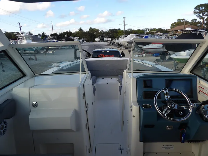 Slide: The Image of 2022 Stingray 269 DC boat interior with steering wheel and seating, docked at marina. - 41